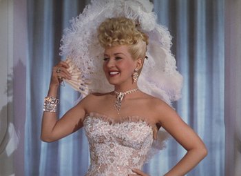 Movie still from “Mother Wore Tights” (1947), directed by Walter Lang – A woman in a white dress holding a white fan; Medium shot, Low angle