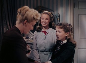 Movie still from “Mother Wore Tights” (1947), directed by Walter Lang – A woman and two young girls are talking to each other; Medium shot, Over the shoulder angle