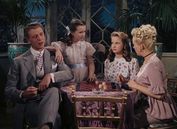 Movie still from “Mother Wore Tights” (1947), directed by Walter Lang – A family playing a game of checkers in a living room; Medium shot, High angle