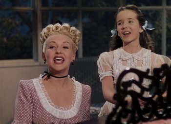 Movie still from “Mother Wore Tights” (1947), directed by Walter Lang – A woman and a young girl are smiling for the camera; Medium shot, Low angle