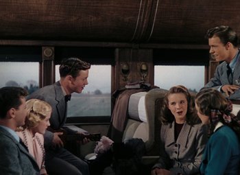 Movie still from “Mother Wore Tights” (1947), directed by Walter Lang – A group of people sitting on a train car; Medium shot, High angle