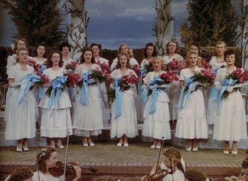 Movie still from “Mother Wore Tights” (1947), directed by Walter Lang – A group of women in white dresses holding pink flowers; Wide shot, High angle