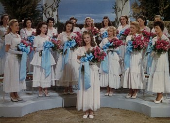 Movie still from “Mother Wore Tights” (1947), directed by Walter Lang – A group of young women standing next to each other holding flowers; Wide shot, High angle