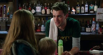 Movie still from “Mother's Day” (2016), directed by Garry Marshall – A man sitting at a table with a bottle and a towel around his neck; Close Up shot, Over the shoulder angle