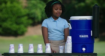 Movie still from “Mother's Day” (2016), directed by Garry Marshall – A young girl standing next to a table with cups on top of it; Medium shot, Over the shoulder angle