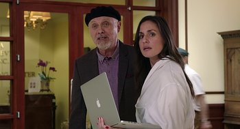 Movie still from “Mother's Day” (2016), directed by Garry Marshall – An older man and a younger woman holding an apple laptop; Medium shot, Over the shoulder angle