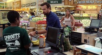 Movie still from “Mother's Day” (2016), directed by Garry Marshall – A man standing at a register in a grocery store; Medium shot, Over the shoulder angle