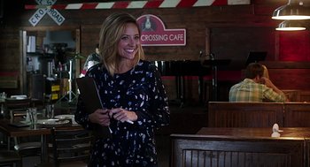 Movie still from “Mother's Day” (2016), directed by Garry Marshall – A woman smiles while holding a book in her hands; Medium shot, Over the shoulder angle
