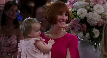 Movie still from “Mother's Day” (2016), directed by Garry Marshall – A woman holding a baby in her arms and smiling; Close Up shot, Over the shoulder angle