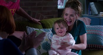 Movie still from “Mother's Day” (2016), directed by Garry Marshall – A woman holding a baby on a couch; Medium shot, Over the shoulder angle