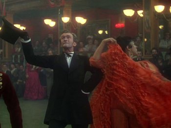 Movie still from “Moulin Rouge” (1952), directed by John Huston – A man in a black suit and a woman in a red dress; Medium shot, Low angle