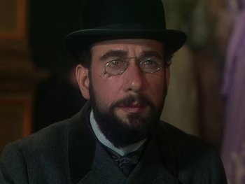 Movie still from “Moulin Rouge” (1952), directed by John Huston – A man with a beard wearing glasses and a hat; Close Up shot, Over the shoulder angle