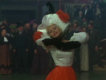 Movie still from “Moulin Rouge” (1952), directed by John Huston – A woman in an orange and white dress is dancing; Medium shot, Low angle