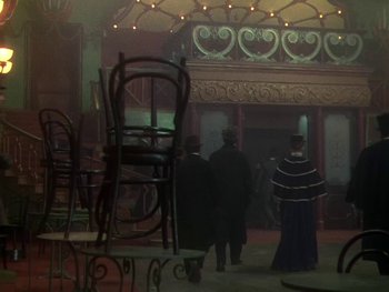 Movie still from “Moulin Rouge” (1952), directed by John Huston – A group of people standing in a room with chairs; Wide shot, High angle