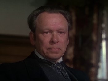 Movie still from “Moulin Rouge” (1952), directed by John Huston – An older man in a suit and tie looking at the camera; Close Up shot, Over the shoulder angle