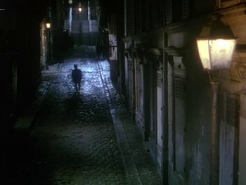 Movie still from “Moulin Rouge” (1952), directed by John Huston – A person walking down a street at night; Extreme Wide shot, High angle