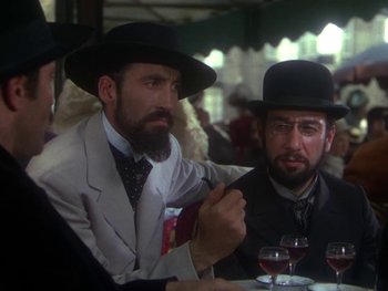 Movie still from “Moulin Rouge” (1952), directed by John Huston – Two men sitting at a table with wine glasses; Medium shot, Over the shoulder angle
