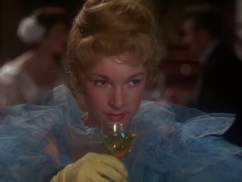 Movie still from “Moulin Rouge” (1952), directed by John Huston – A woman in a blue dress holding a glass of wine; Close Up shot, Over the shoulder angle