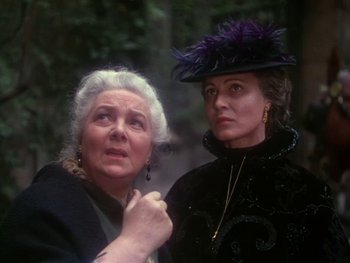Movie still from “Moulin Rouge” (1952), directed by John Huston – Two older women standing next to each other in a forest; Close Up shot, Over the shoulder angle