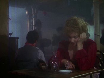Movie still from “Moulin Rouge” (1952), directed by John Huston – A woman sitting at a table with a man in the background; Medium shot, Over the shoulder angle