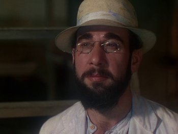 Movie still from “Moulin Rouge” (1952), directed by John Huston – A man with a beard wearing glasses and a hat; Close Up shot, Over the shoulder angle