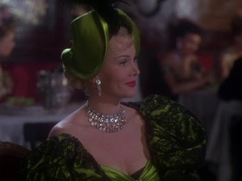 Movie still from “Moulin Rouge” (1952), directed by John Huston – A woman wearing a green dress and a green hat; Medium shot, Over the shoulder angle