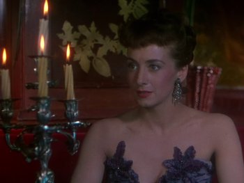 Movie still from “Moulin Rouge” (1952), directed by John Huston – A woman sitting in front of a lit candle holder; Close Up shot, Over the shoulder angle