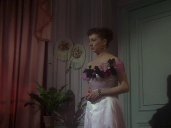 Movie still from “Moulin Rouge” (1952), directed by John Huston – A woman in a white dress holding a pink flower; Medium shot, Low angle