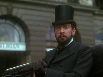 Movie still from “Moulin Rouge” (1952), directed by John Huston – A man in a top hat and glasses holding a gun; Close Up shot, Low angle