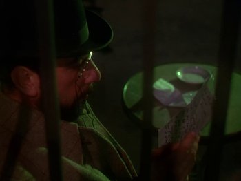 Movie still from “Moulin Rouge” (1952), directed by John Huston – A man in a green hat is looking at a piece of paper in front of him; Close Up shot, Over the shoulder angle