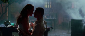 Movie still from “Mr. & Mrs. Smith” (2005), directed by Doug Liman – A man and a woman sitting at a table kissing; Medium shot, Low angle