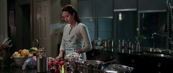 Movie still from “Mr. & Mrs. Smith” (2005), directed by Doug Liman – A woman standing in front of a counter preparing food in a kitchen; Medium shot, Over the shoulder angle