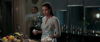 Movie still from “Mr. & Mrs. Smith” (2005), directed by Doug Liman – A woman in a kitchen holding a bowl of food; Medium shot, Over the shoulder angle