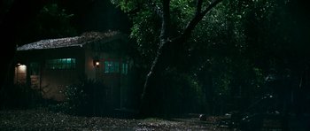 Movie still from “Mr. & Mrs. Smith” (2005), directed by Doug Liman – A house in the woods at night with a light shining on it; Extreme Wide shot, High angle