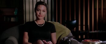 Movie still from “Mr. & Mrs. Smith” (2005), directed by Doug Liman – A woman sitting in a chair wearing a black shirt; Medium shot, Over the shoulder angle