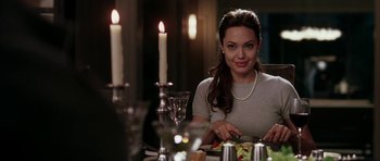 Movie still from “Mr. & Mrs. Smith” (2005), directed by Doug Liman – A woman sitting at a table with a plate of food in front of candles; Medium shot, Over the shoulder angle