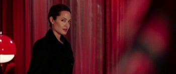 Movie still from “Mr. & Mrs. Smith” (2005), directed by Doug Liman – A woman standing in front of a red curtain; Medium shot, Over the shoulder angle