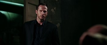 Movie still from “Mr. & Mrs. Smith” (2005), directed by Doug Liman – A man wearing a suit and tie standing in a dark room; Close Up shot, Low angle