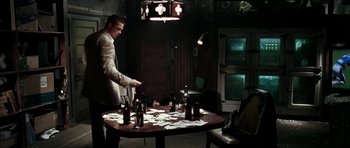 Movie still from “Mr. & Mrs. Smith” (2005), directed by Doug Liman – A man standing at a table with a bunch of beer bottles; Wide shot, Over the shoulder angle