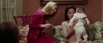 Movie still from “Mr. & Mrs. Smith” (2005), directed by Doug Liman – Two women sitting on a chair and one is holding a wine glass and the other is holding a bottle; Medium shot, Over the shoulder angle