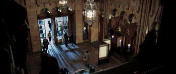 Movie still from “Mr. & Mrs. Smith” (2005), directed by Doug Liman – People are standing in a large room with a light fixture hanging from the ceiling; Extreme Wide shot, High angle