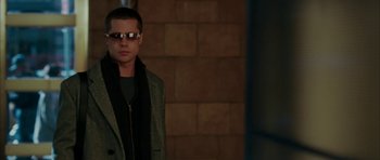 Movie still from “Mr. & Mrs. Smith” (2005), directed by Doug Liman – A man wearing a jacket and sunglasses standing in front of a brick wall; Medium shot, Low angle