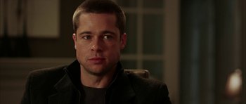 Movie still from “Mr. & Mrs. Smith” (2005), directed by Doug Liman – A person sitting in a chair wearing a jacket; Close Up shot, Over the shoulder angle