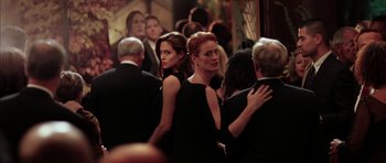 Movie still from “Mr. & Mrs. Smith” (2005), directed by Doug Liman – A group of people standing around each other at an event; Medium shot, Over the shoulder angle