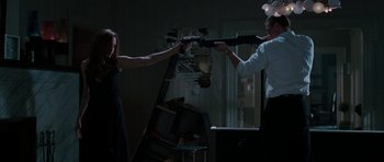 Movie still from “Mr. & Mrs. Smith” (2005), directed by Doug Liman – A man and a woman holding guns in a dark room; Medium shot, Low angle