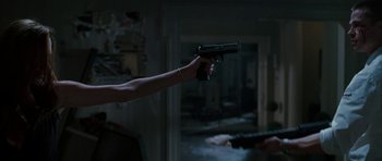 Movie still from “Mr. & Mrs. Smith” (2005), directed by Doug Liman – A person holding a gun in a dark room; Medium shot, Low angle