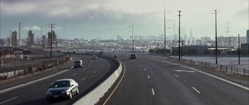 Movie still from “Mr. & Mrs. Smith” (2005), directed by Doug Liman – Cars driving down a highway with a city in the background; Extreme Wide shot, High angle