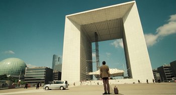 Movie still from “Mr. Bean's Holiday” (2007), directed by Steve Bendelack – A man standing in front of a large white building; Extreme Wide shot, Low angle