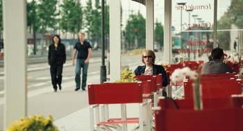 Movie still from “Mr. Bean's Holiday” (2007), directed by Steve Bendelack – A woman sitting at a table outside of a restaurant; Wide shot, Over the shoulder angle
