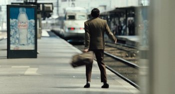 Movie still from “Mr. Bean's Holiday” (2007), directed by Steve Bendelack – A man walking on a train platform while holding a bag; Wide shot, High angle